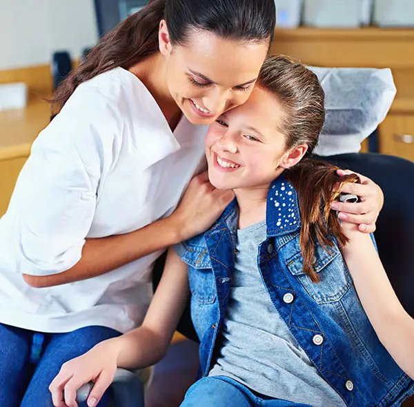a mother hugging her daughter in a dental chair